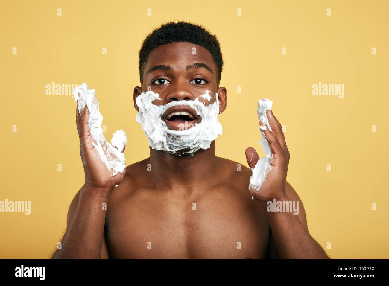 handsome shirtless Afro guy with smeared face and hands with foam. close up photo. Stock Photo