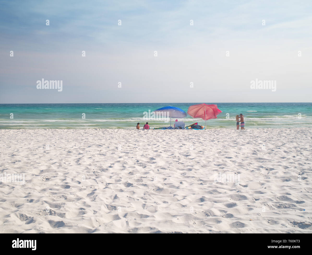 Blurred motion of umbrellas people and waves. Stock Photo