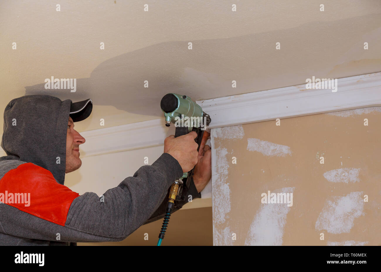 Construction worker nailed moulding wall in the new house Stock Photo