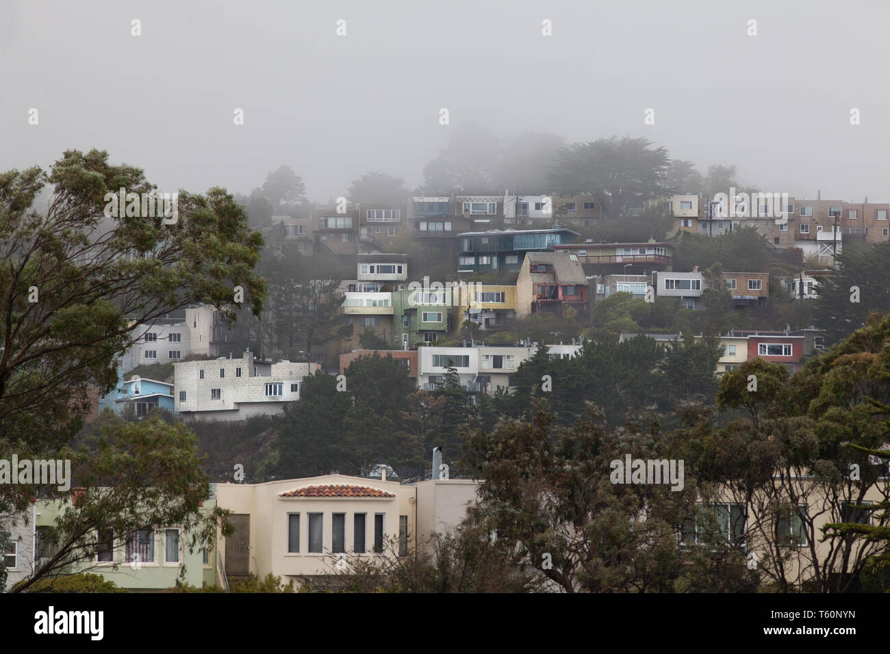 Foggy hillside crowded with homes in a San Francisco neighborhood. Stock Photo