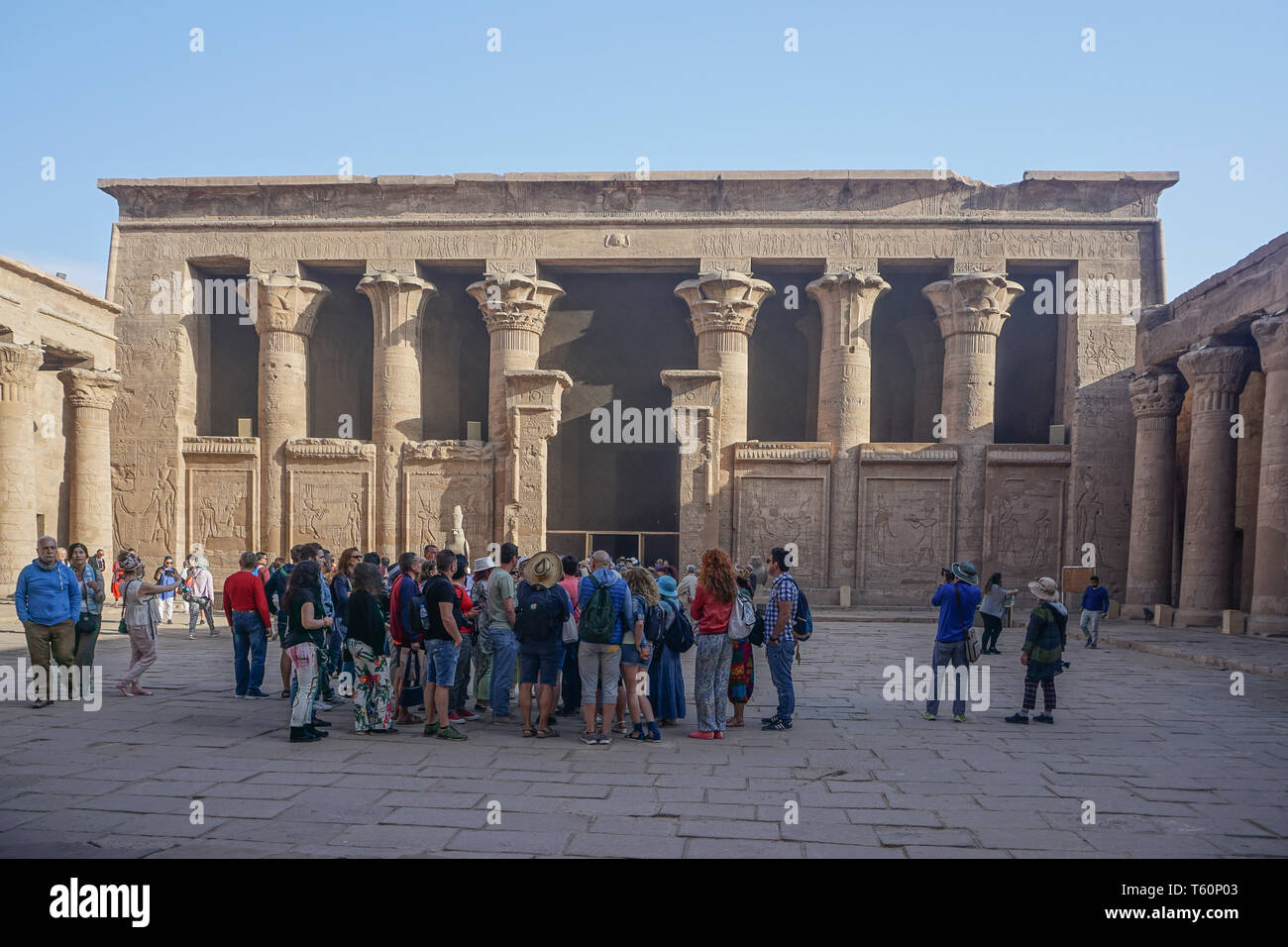 Edfu, Egypt: Tourists listen to their guide in the courtyard of the temple of Edfu, the largest temple dedicated to Horus and Hathor of Dendera. Stock Photo