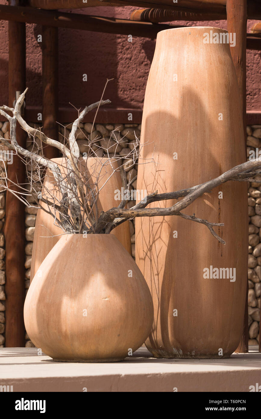group or collection of terracotta or ceramic landscape pots on a patio or balcony outdoors with dry tree branches as exterior decor in Africa Stock Photo