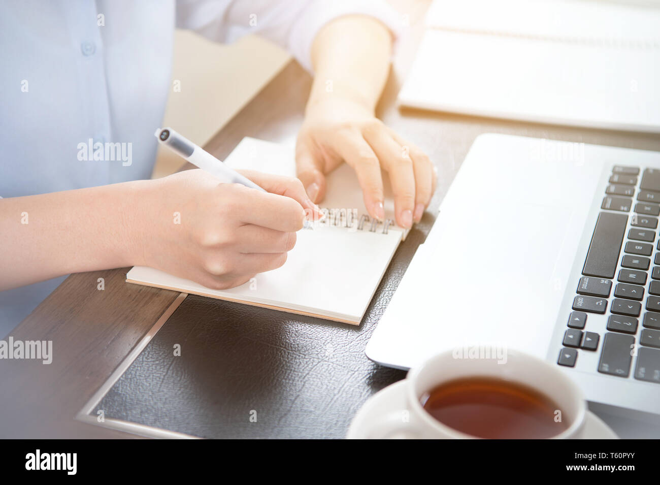 Business concept. Woman takes note for project with laptop and report in office desk