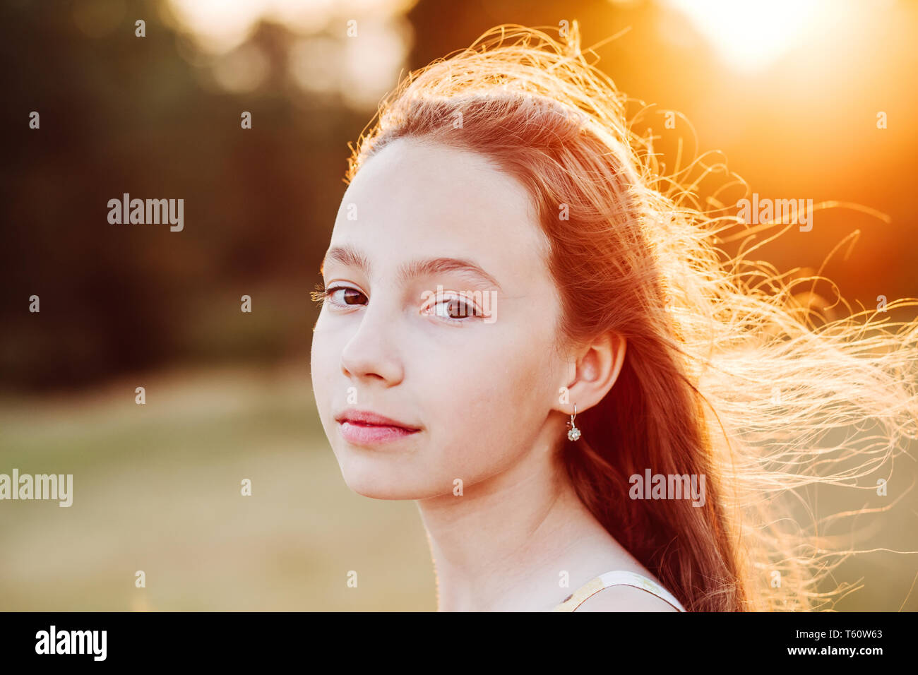 Portrait of Beautiful serious Teen Girl is enjoying nature in the park at Summer sunset Stock Photo