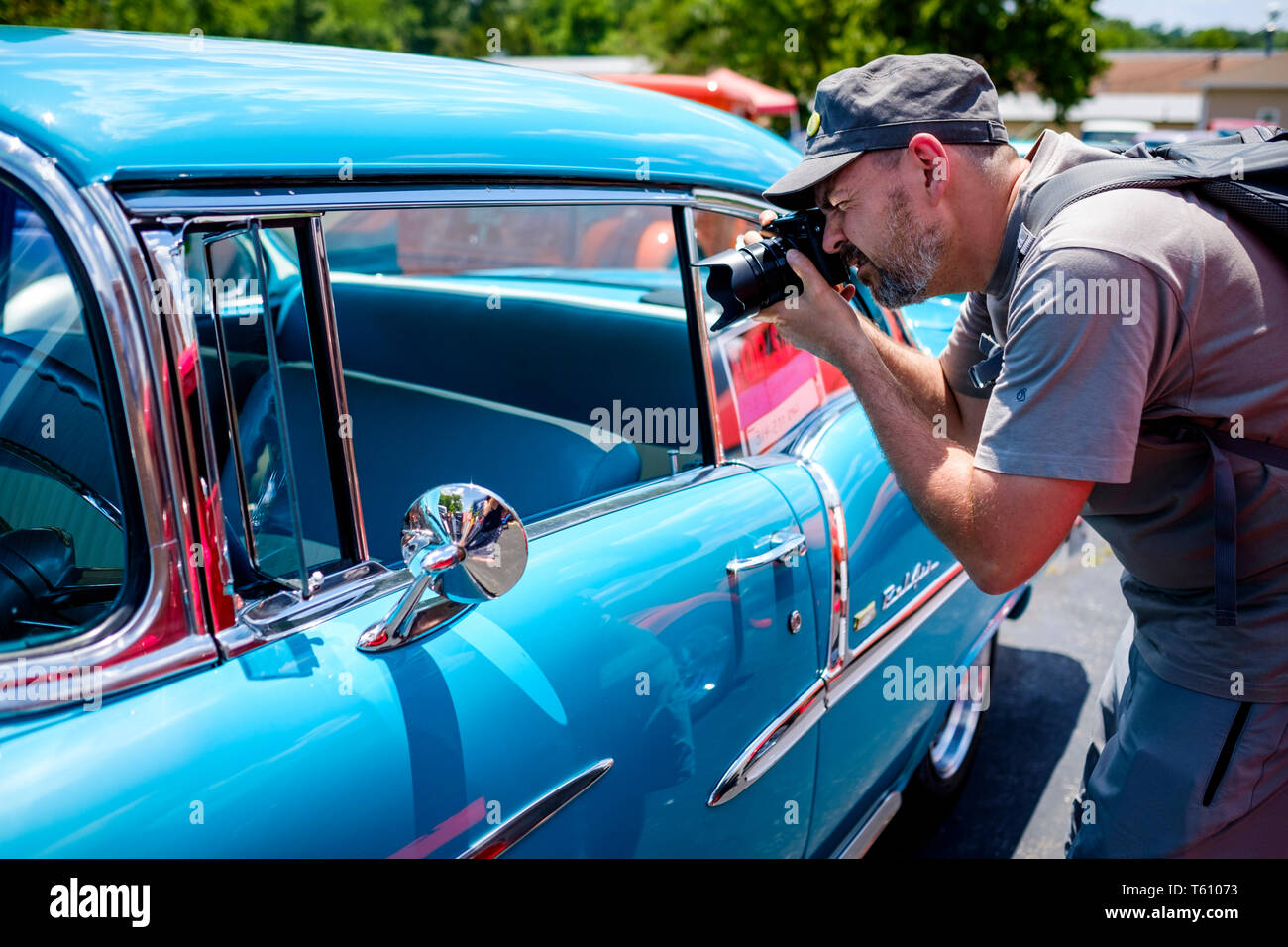 White male visitor taking photographs at an openair classics car show