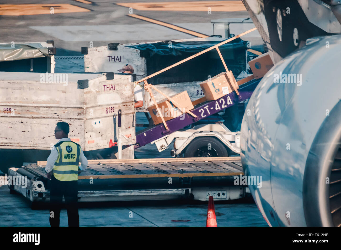 Asian ground crew loading cargo, mail, and luggage including cardboard box into back cargo bay at the airport Stock Photo