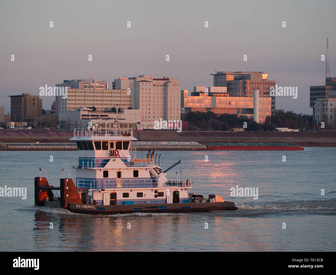 Port Allen, Louisiana, USA - 2019: Downtown Baton Rouge is seen from across the Mississippi River as a towboat travels upstream. Stock Photo