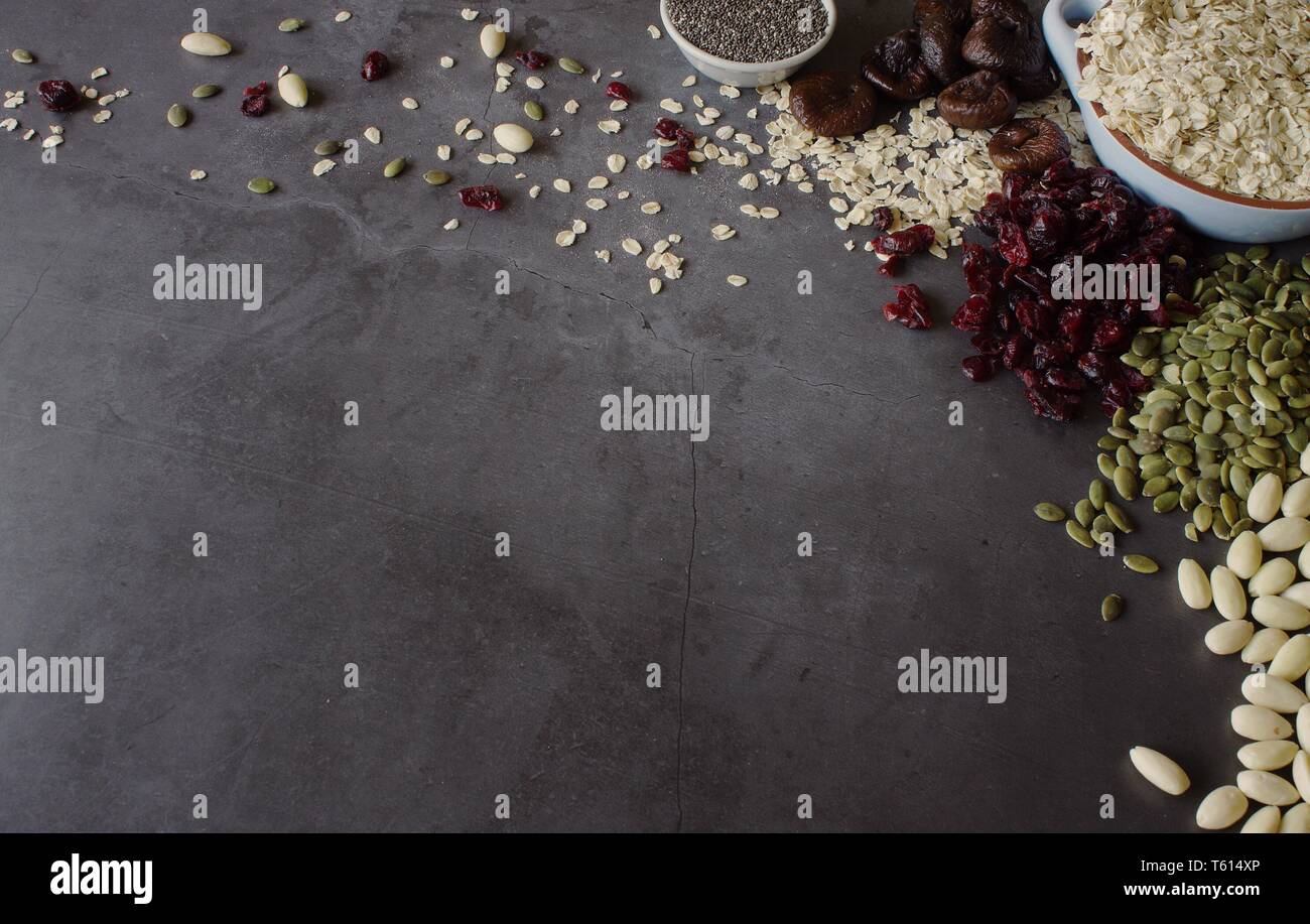 Raw oats with dried fruit, seeds and nuts on grey slate background with