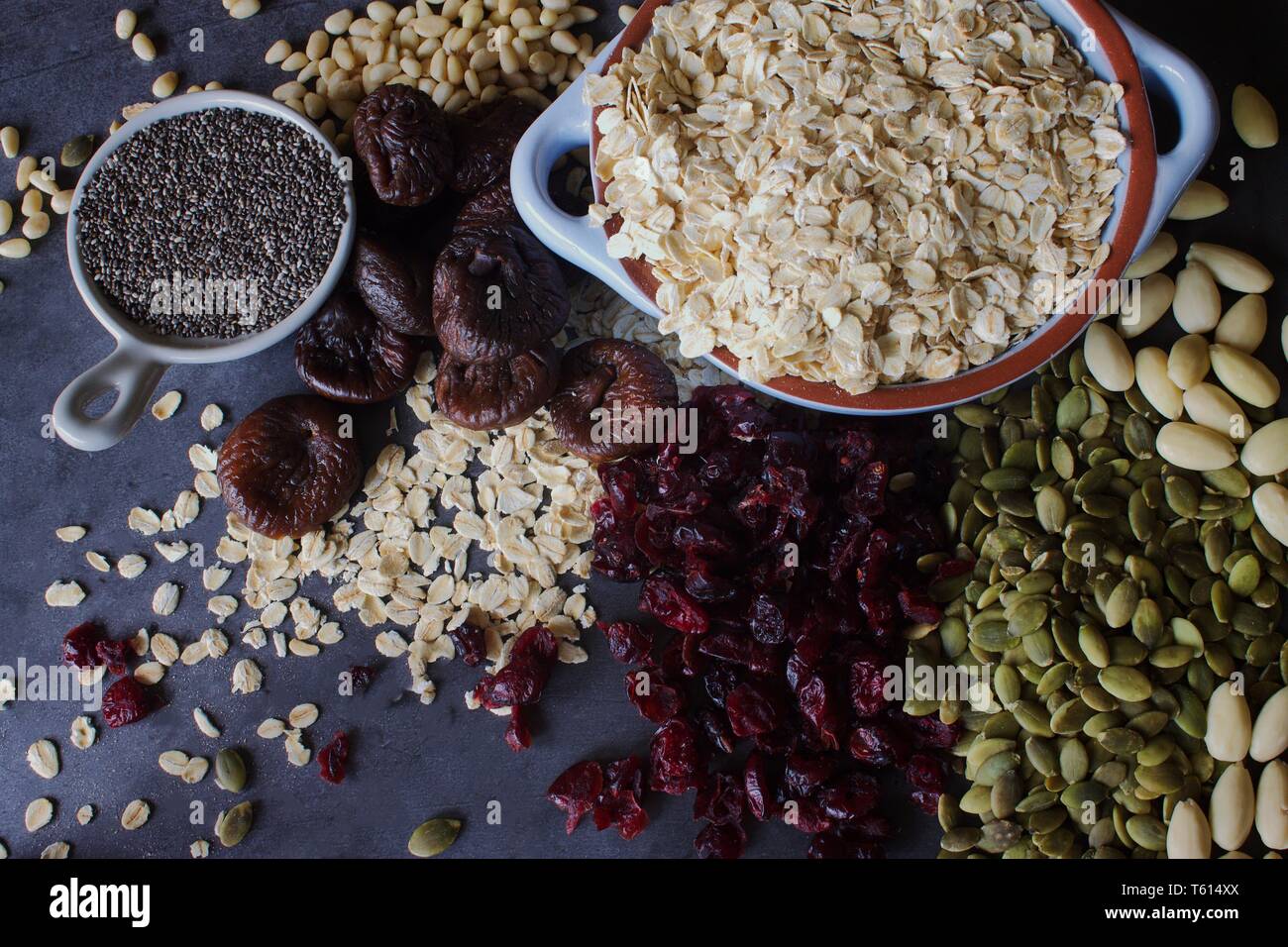 Raw oats with dried fruit, nuts and seeds on a grey slate background