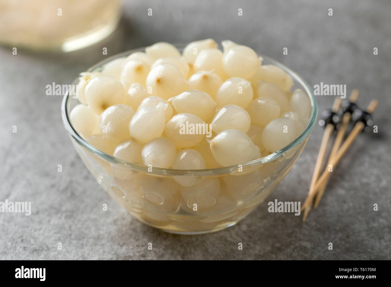 Glass bowl with traditional pickled silverskin onions close up Stock