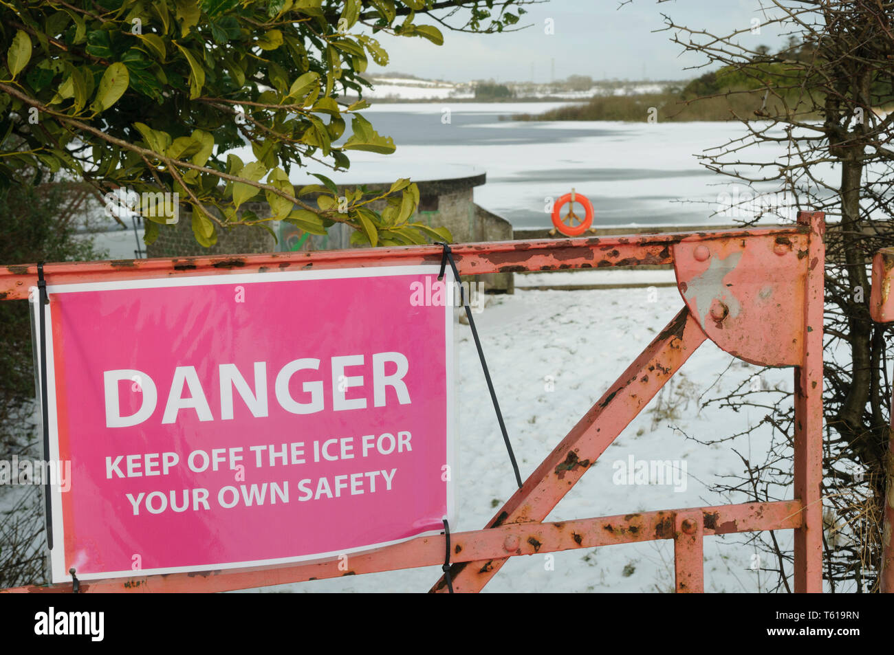 Warning sign on a gate beside a frozen lake 'Danger - For your own safety, keep off the ice' Stock Photo