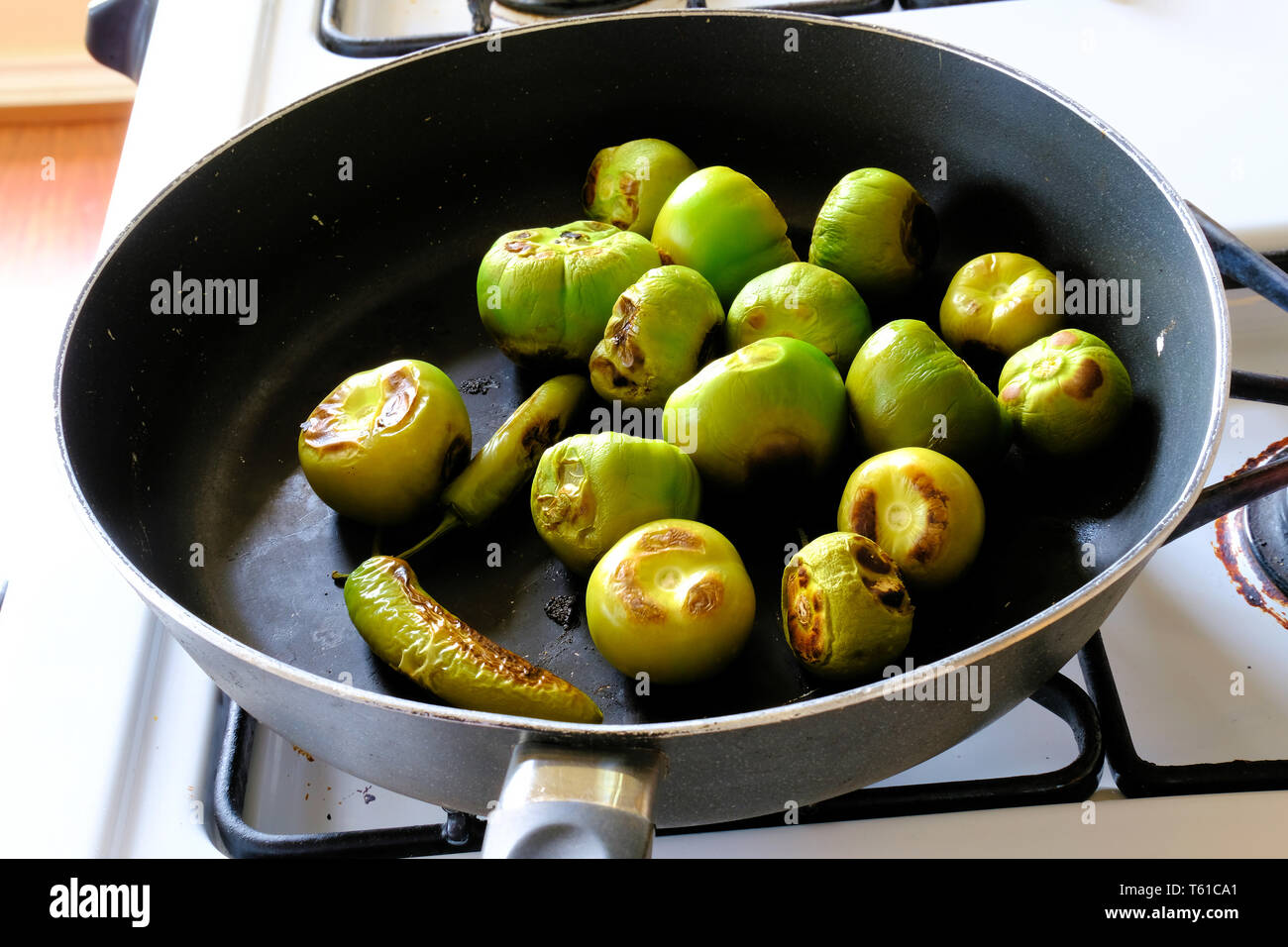 Roasted green tomatillos and serrano peppers in a pan used for roasting