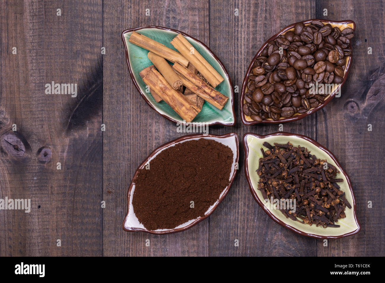 Four cups with coffee beans, cinnamon, cloves and coffee powder Stock
