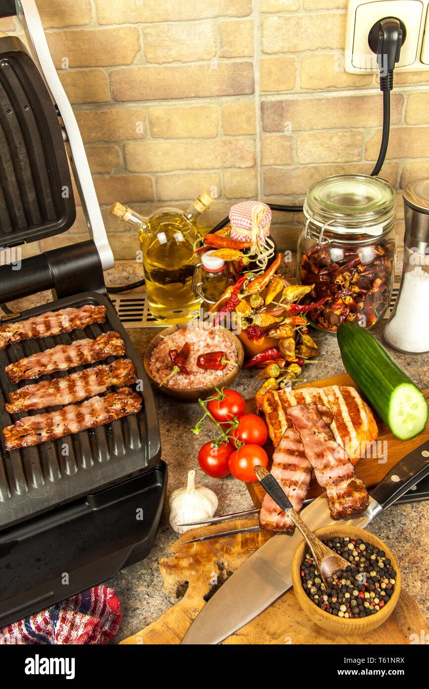 Grill steak on an electric stove. Pork neck fried on small electric grill.  Home cooking. Healthy barbecue. Catering to friends. Electric grilling.  Stock Photo