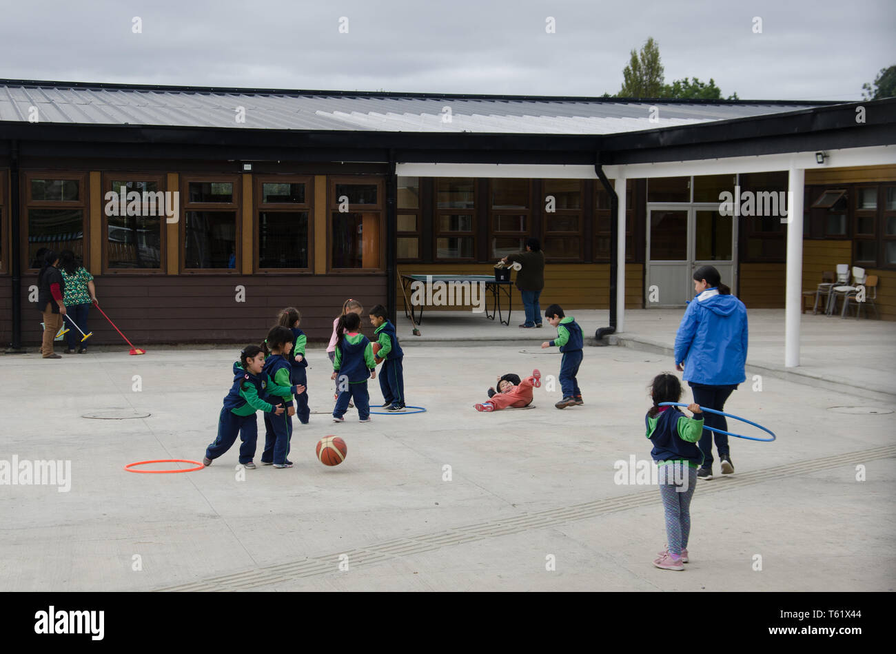 Small children at play in their schoolyard next to Nercon's wooden church on Chiloé island, Chile Stock Photo