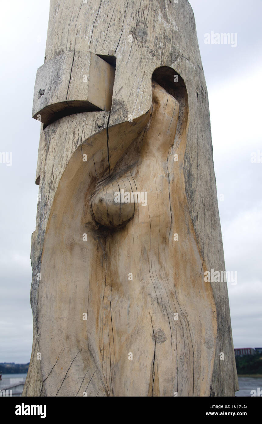 Near the water's edge in Castro, Chiloé island, a wooden carving includes a female form; Chilotes are strong believers in water spireits and mythology Stock Photo