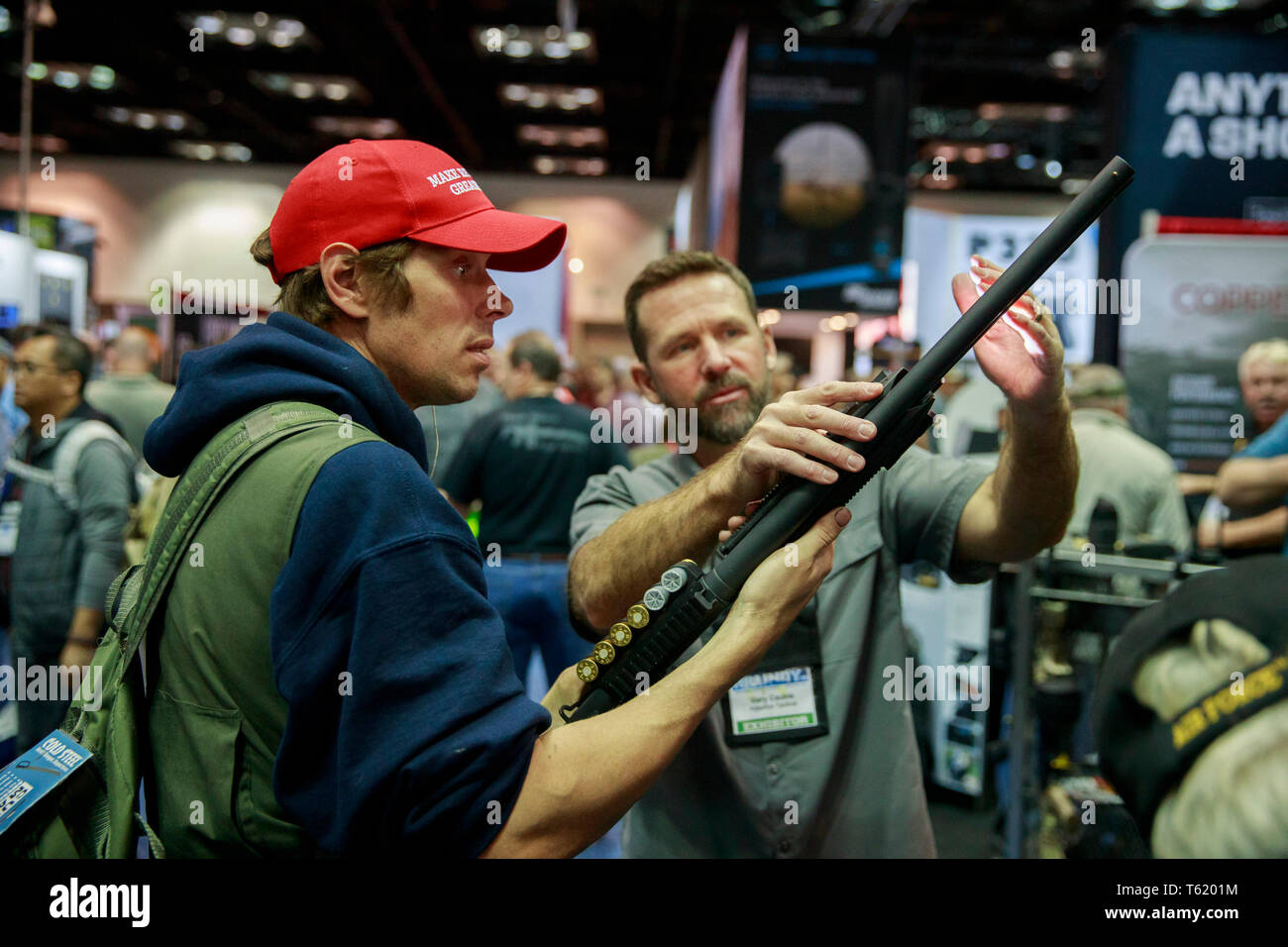 An NRA member and Trump supporter wearing a MAGA hat looks at a shotgun during the third day of the National Rifle Association convention. Stock Photo