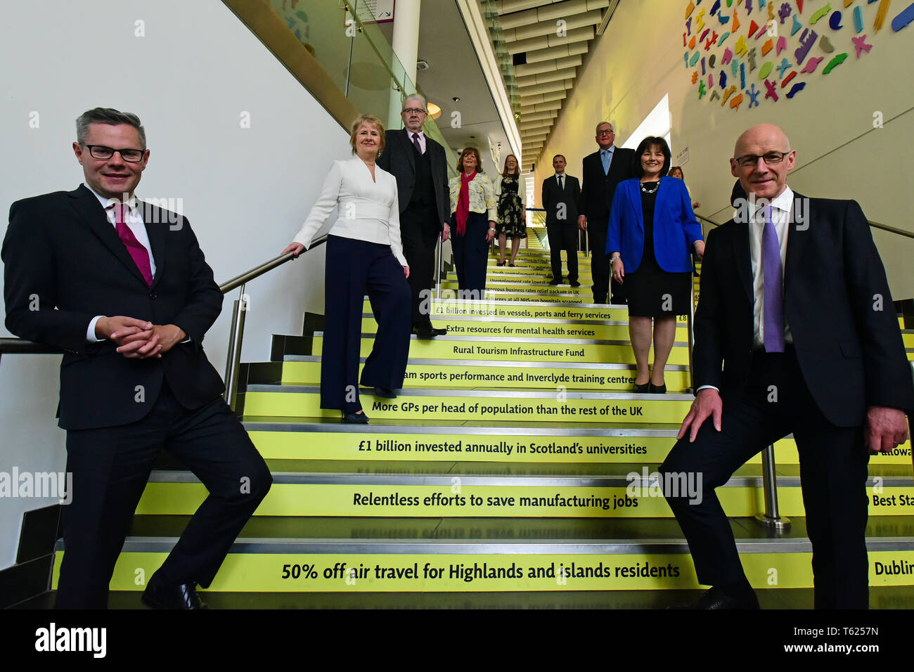 Edinburgh, UK. 28, April, 2019. Scotland's Deputy First Minister John Swinney (R) and Cabinet Secretaries pose for photographs on a staircase proclaiming several of the Scottish Government's claimed achievements at  the Scottish National Party's  Spring Conference in the Edinburgh International Conference Centre, © Ken Jack / Alamy Live News Stock Photo