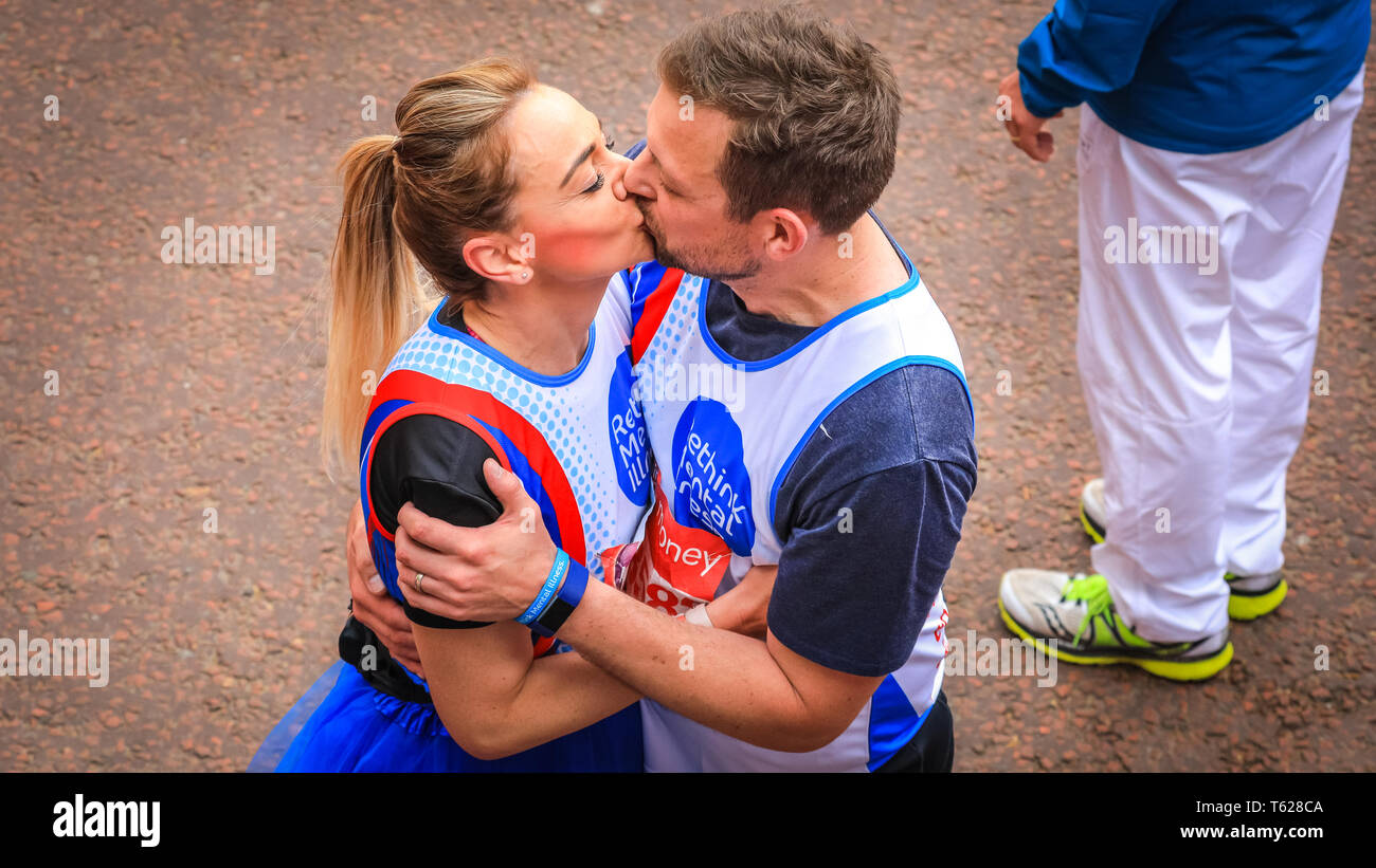 London, UK. 28th Apil 2019. A couple running their race for the Mental Health Charity 'Rethink Mental Illness' kiss as they cross the finish line. Over 40,000 starters are once again competing in the Virgin London Marathon, including those who take on the race for charities, in running clubs, in memory of loved ones and as personal lifetime goals. Credit: Imageplotter/Alamy Live News Stock Photo