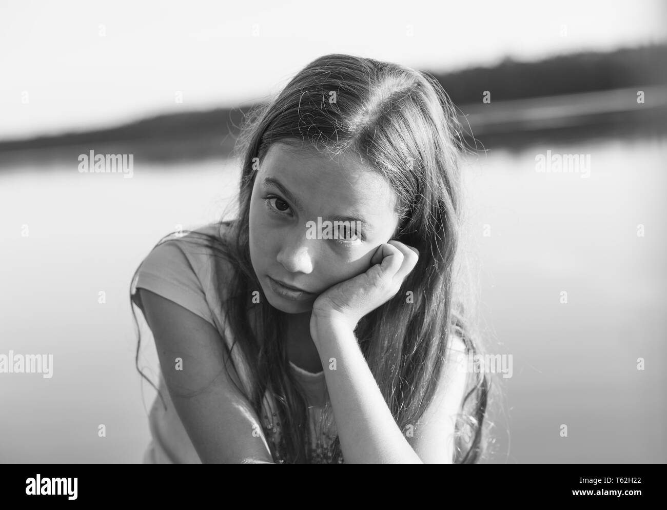 Black and white portrait of Sad Beautiful teen girl looking with serious face at seaside during sunset Stock Photo