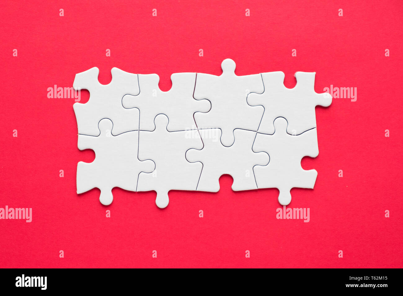 Eight pieces white jigsaw puzzle on red background for business presentation Stock Photo