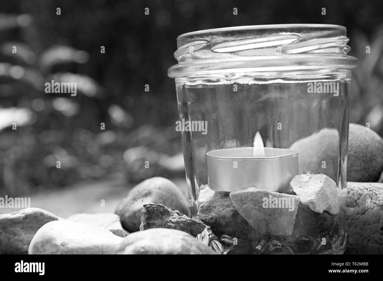 black and white burning tea light candle glass stones right grasses