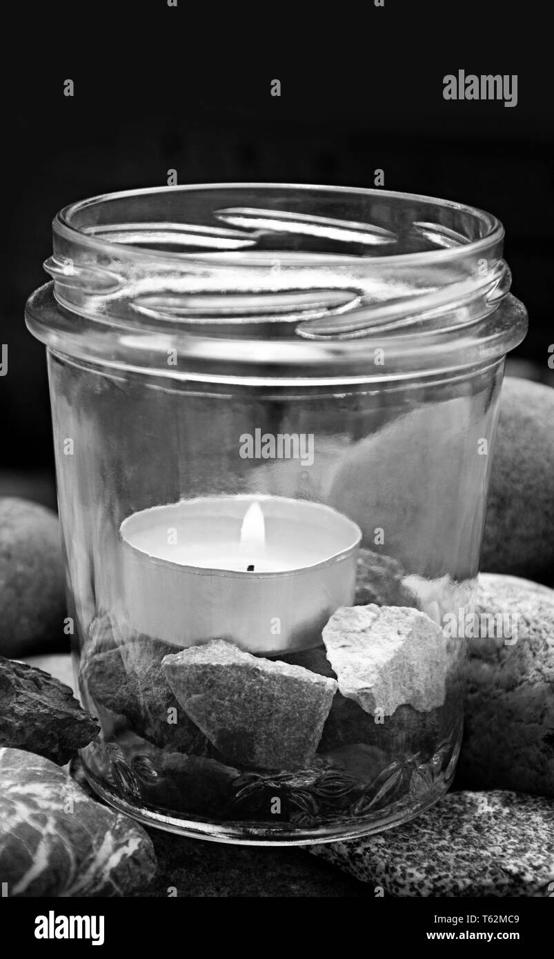 upright black and white burning tea light candle glass stones center