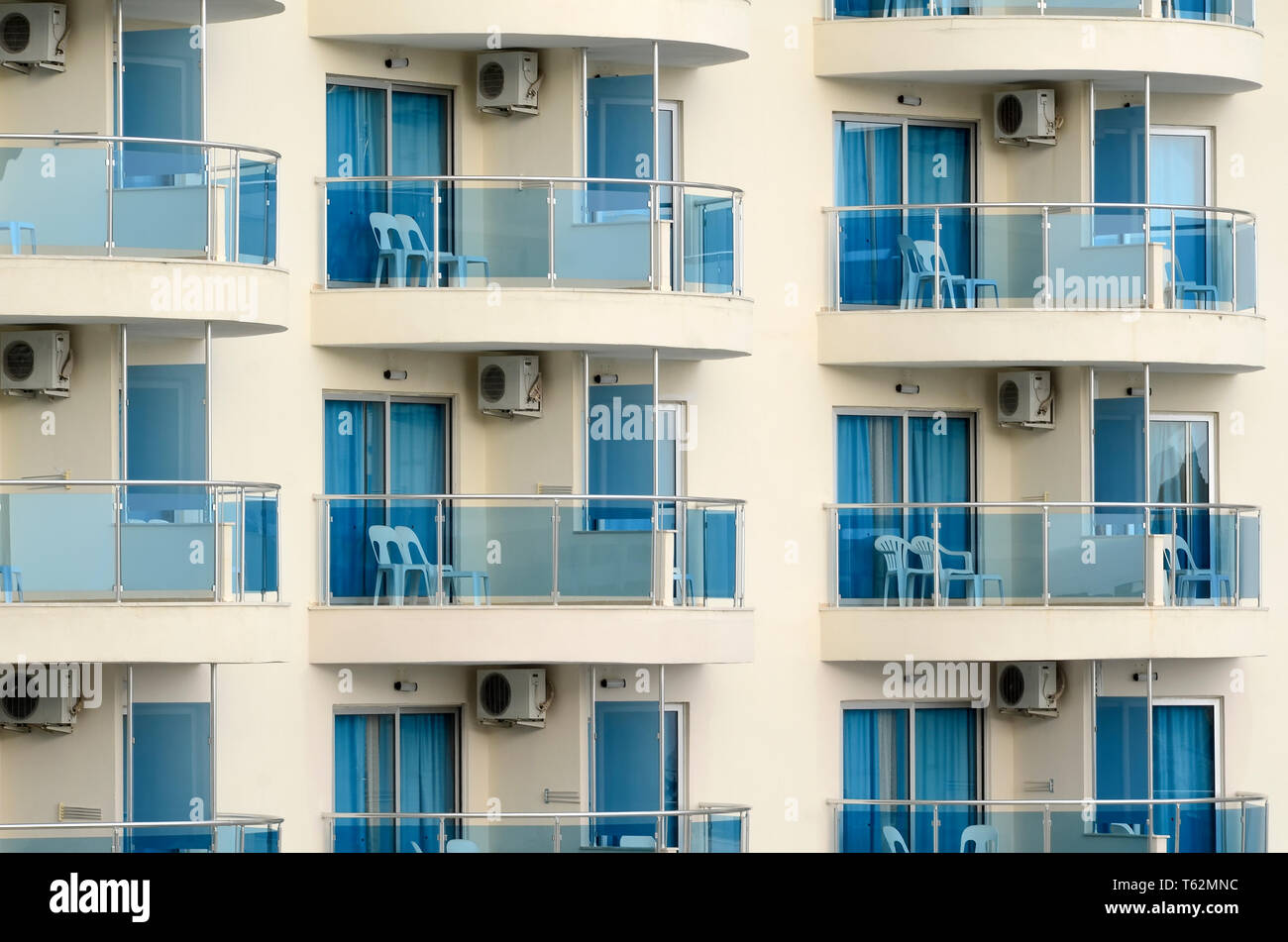 Standard balconies of a large hotel with plastic chairs on them Stock Photo