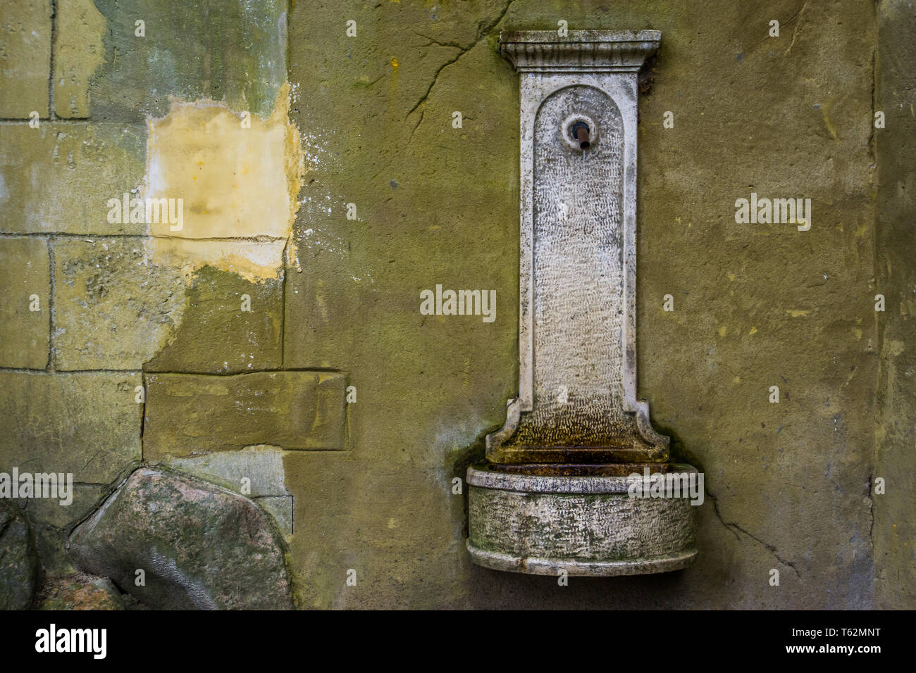 old vintage drinking water fountain hanging on a stone wall, historical