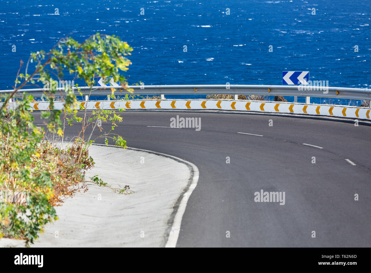 View along a road into a curve with the sea in the background in the east of La Palma, Spain near Mazo Stock Photo
