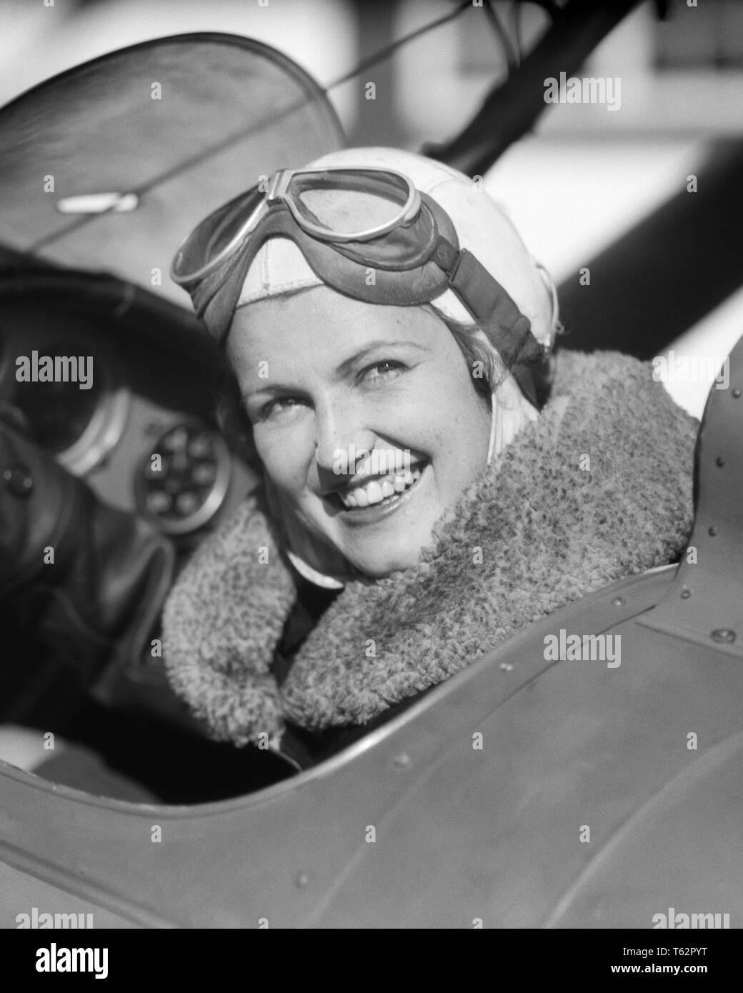 1930S woman pilot sitting in cockpit of airplane smiling looking at camera fur collar on jacket and goggles pushed up on head - a4370 HAR001 HARS FACIAL STYLE WELCOME PLEASED JOY LIFESTYLE PLANES FEMALES JOBS LADIES PERSONS GOGGLES RISK CONFIDENCE TRANSPORTATION EXPRESSIONS B&W EYE CONTACT SKILL OCCUPATION HAPPINESS SKILLS THRILL HEAD AND SHOULDERS CHEERFUL ADVENTURE AIRPLANES AND AT IN OF ON AVIATION EMPLOYMENT OCCUPATIONS PUSHED SMILES COCKPIT FUR COLLAR AVIATOR JOYFUL STYLISH AVIATRIX MID-ADULT MID-ADULT WOMAN BLACK AND WHITE BRAVE CAUCASIAN ETHNICITY HAR001 OLD FASHIONED Stock Photo