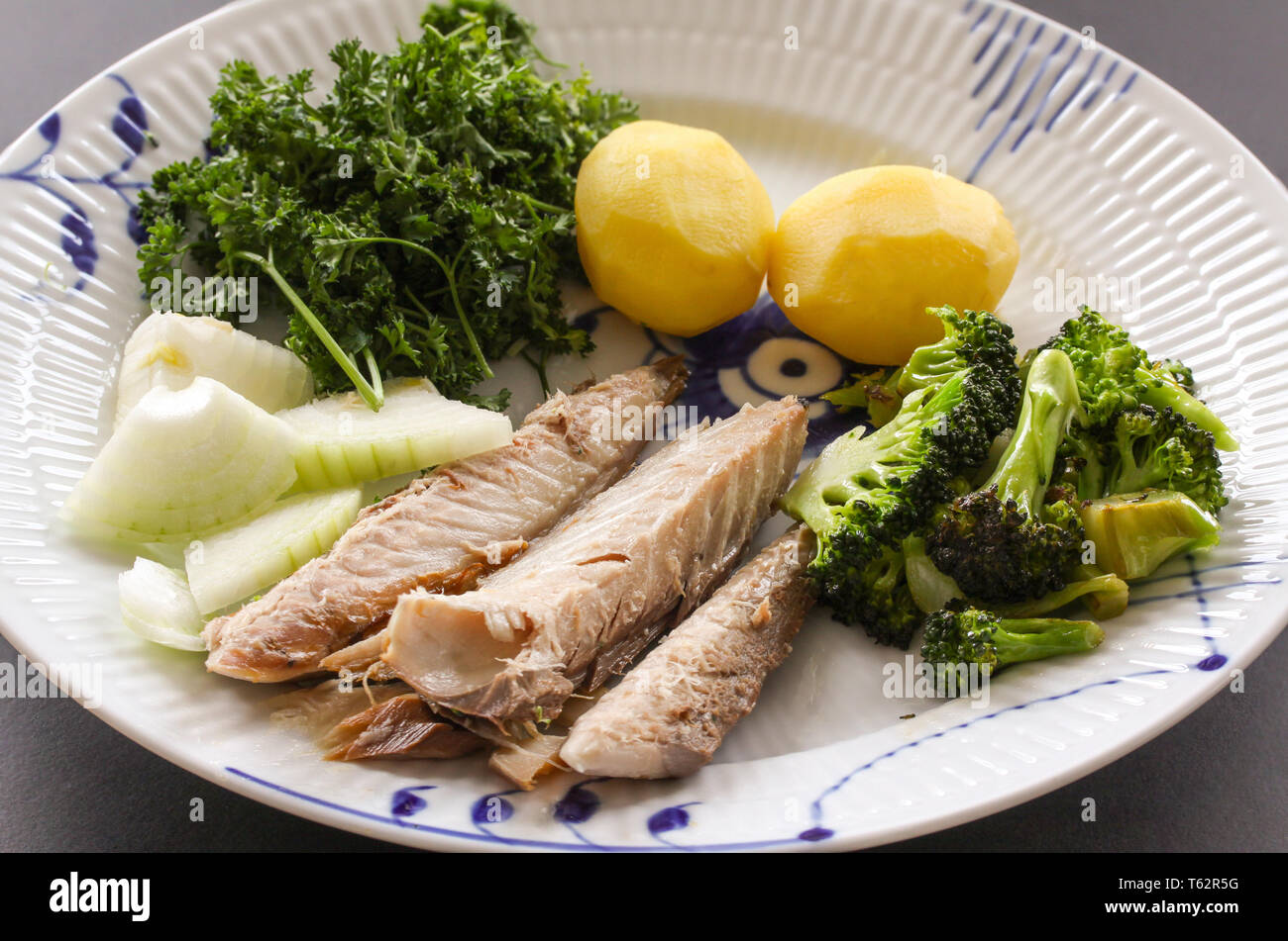 Mackerel fish dish with potatoes, broccoli, onions and parley. Fatty, oily fish is an excellent and healthy source of DHA and EPA, which are two key t Stock Photo