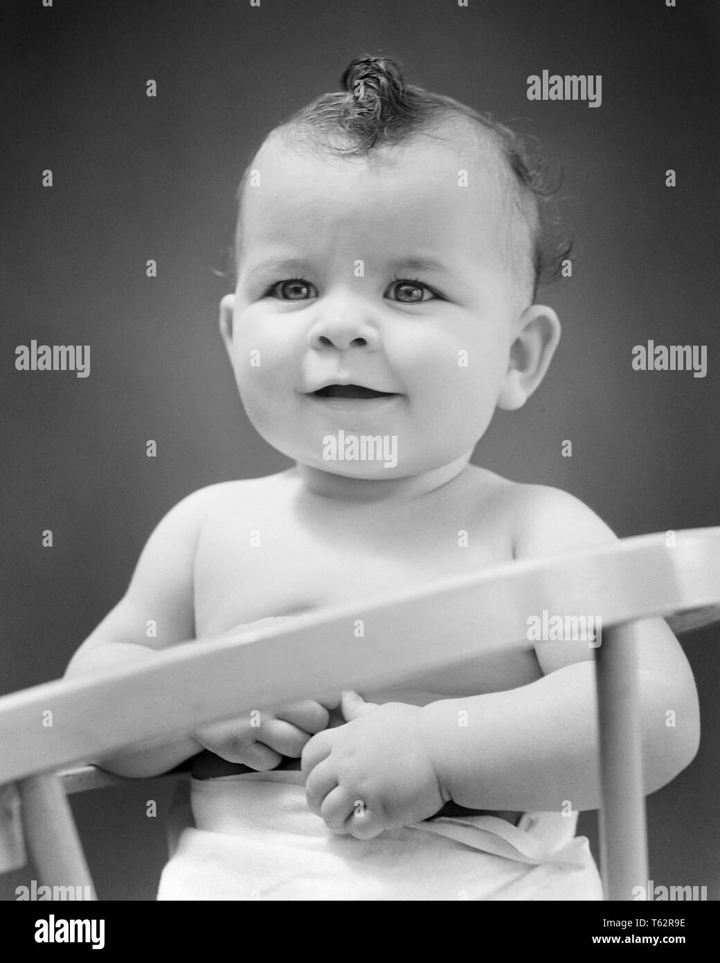 1940s PLEASANT ONE YEAR OLD  GIRL TODDLER SITTING UP IN SAFETY BABY CHAIR - b13446 HAR001 HARS ALERT CONTAINED PLEASANT GROWTH JUVENILES BABY GIRL BLACK AND WHITE CAUCASIAN ETHNICITY HAR001 OLD FASHIONED Stock Photo
