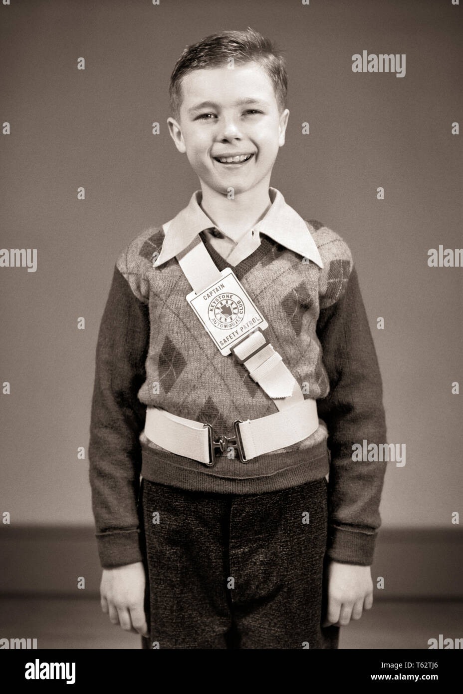 1940s PORTRAIT OF BRIGHT SMILING BOY WEARING ELEMENTARY SCHOOL SAFETY
