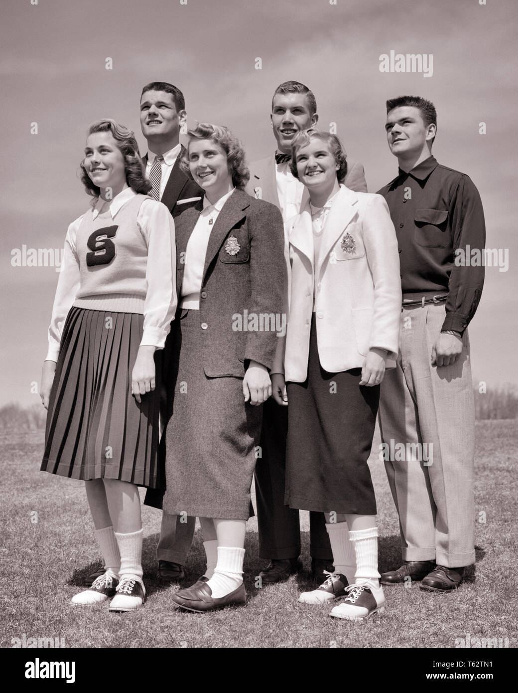 1950s group portrait of standing SMILING high school teenagers BOYS AND GIRLS  - j7050 HAR001 HARS LIFESTYLE FEMALES HEALTHINESS COPY SPACE FRIENDSHIP FULL-LENGTH MALES TEENAGE GIRL SIX TEENAGE BOY B&W SKIRTS GOALS SUIT AND TIE DREAMS HAPPINESS CHEERFUL STYLES LEADERSHIP LOW ANGLE OF HIGH SCHOOL SMILES HIGH SCHOOLS CONNECTION SADDLE OXFORDS BLAZERS FRIENDLY JOYFUL STYLISH BOBBY SOX COOPERATION FASHIONS GROWTH JUVENILES SCHOOLMATES TOGETHERNESS BLACK AND WHITE BOBBY SOCKS CAUCASIAN ETHNICITY CLASSMATES HAR001 OLD FASHIONED Stock Photo