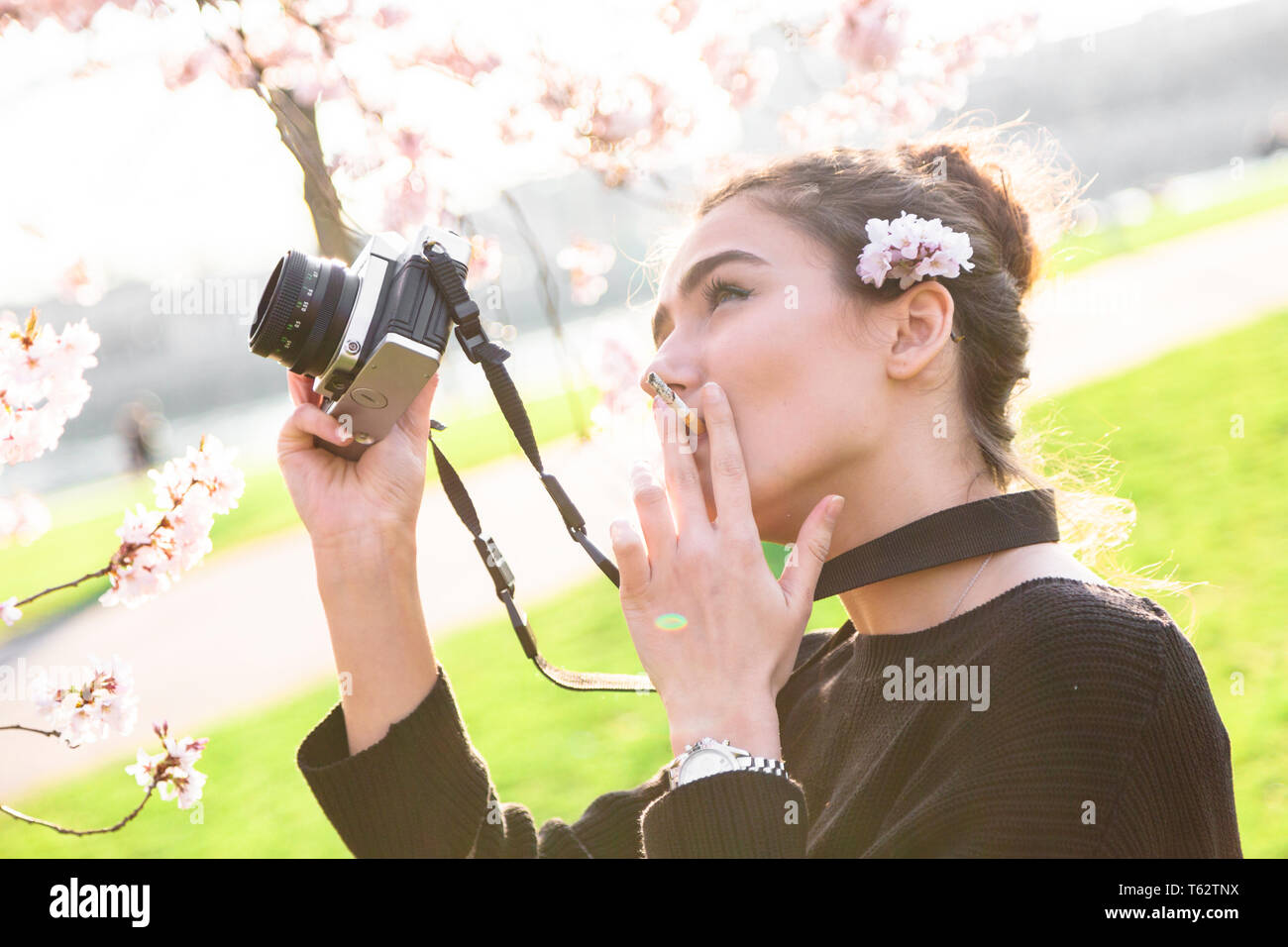 Woman photographer smokes outdoor, camera in hands Stock Photo