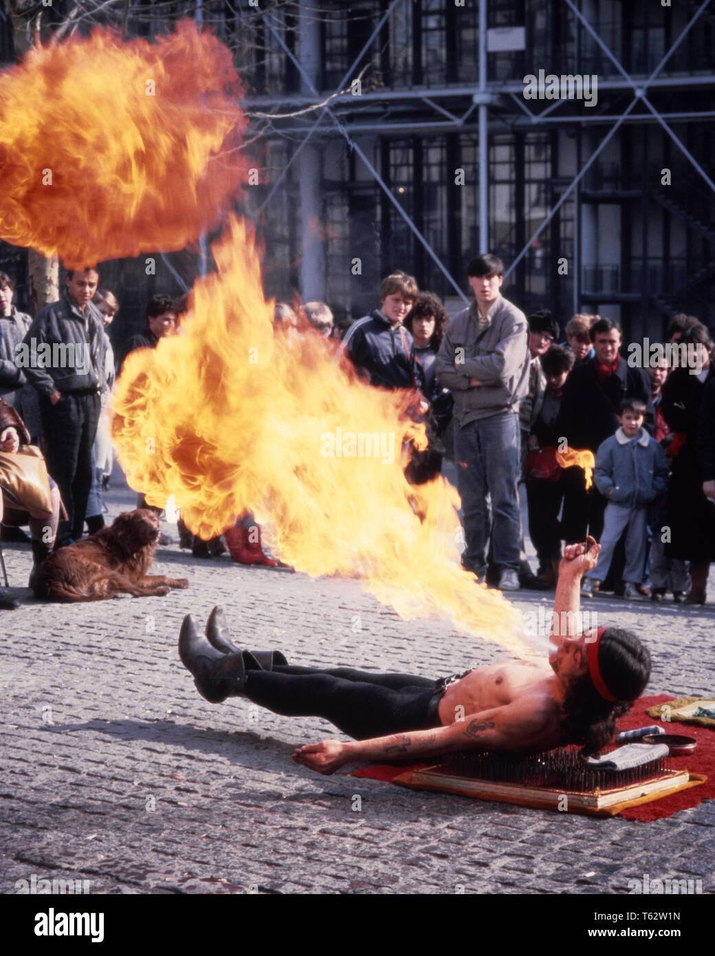 1980s FIRE BREATHER STREET PERFORMANCE ARTIST PARIS FRANCE - kc10630 PHT001 HARS RISK ARTIST PERFORMANCE PROFESSION ENTERTAINMENT SPIRITUALITY CONFIDENCE PERFORMING PERFORMING ARTS SKILL OCCUPATION SKILLS ADVENTURE PERFORMER STRENGTH COURAGE CAREERS EXCITEMENT POWERFUL ENTERTAINER OCCUPATIONS PLACES MOTION BLUR CONCEPTUAL ACTORS STYLISH EATER ENTERTAINERS FIRE BREATHING PERFORMERS YOUNG ADULT MAN CAUCASIAN ETHNICITY OLD FASHIONED Stock Photo