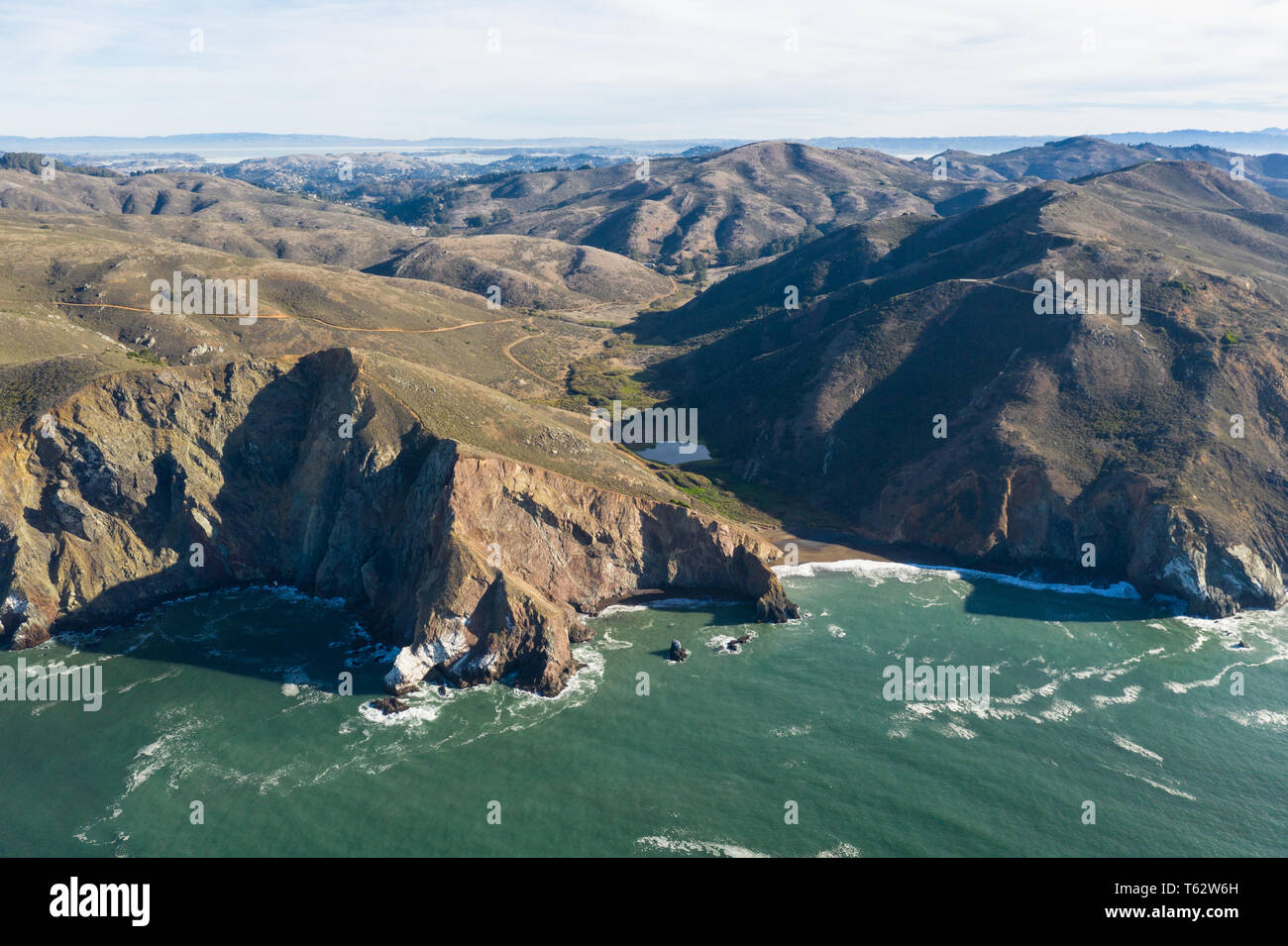 Seen from an aerial perspective, the cold waters of the Pacific Ocean wash against the rocky Northern California coastline in Marin. Stock Photo