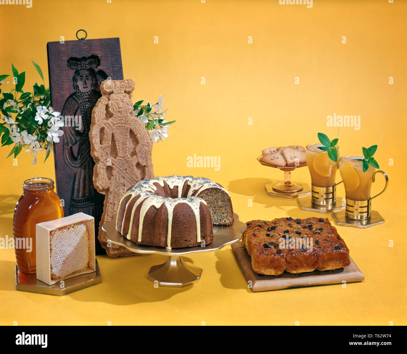 1970s HONEY BAKED GOODS STICKY BUNS GLAZED BUNDT CAKE WITH POPPY SEEDS HONEYCOMB JAR OF HONEY TWO MINT COOLER DRINKS AND COOKIES - kf11430 FRT001 HARS OLD FASHIONED Stock Photo