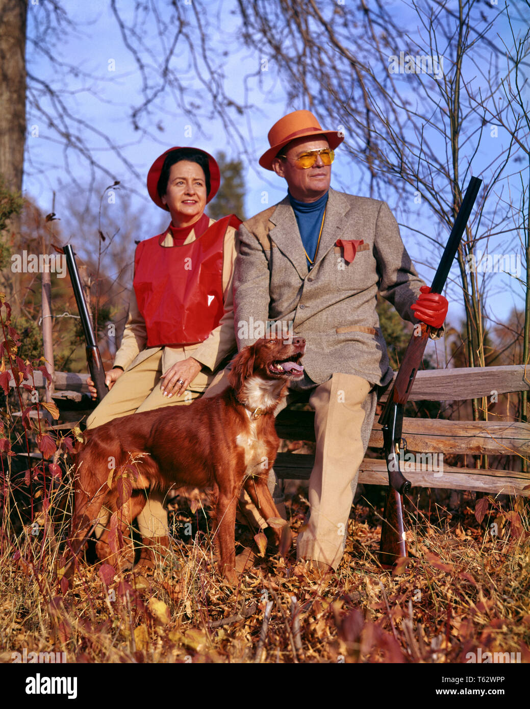 1960s EXPERIENCED COUPLE DRESSED FOR UPLAND GAME BIRD HUNTING HOLDING SHOTGUNS SITTING ON RAIL FENCE BESIDE IRISH SETTER DOG  - kg2769 HAR001 HARS HUNTING OLD TIME NOSTALGIA OLD FASHION 1 FACIAL STYLE SAFETY TEAMWORK GUNS VACATION ATHLETE RELAXING JOY LIFESTYLE FEMALES MARRIED RURAL SPOUSE HUSBANDS HEALTHINESS COPY SPACE FULL-LENGTH LADIES PHYSICAL FITNESS PERSONS MALES ATHLETIC CONFIDENCE EXPRESSIONS MIDDLE-AGED PARTNER MIDDLE-AGED MAN SUCCESS TIME OFF SKILL ACTIVITY AMUSEMENT SPORTING HAPPINESS MAMMALS WELLNESS ADVENTURE HOBBY LEISURE STRENGTH STYLES TRIP INTEREST GETAWAY EXPERIENCED CANINES Stock Photo