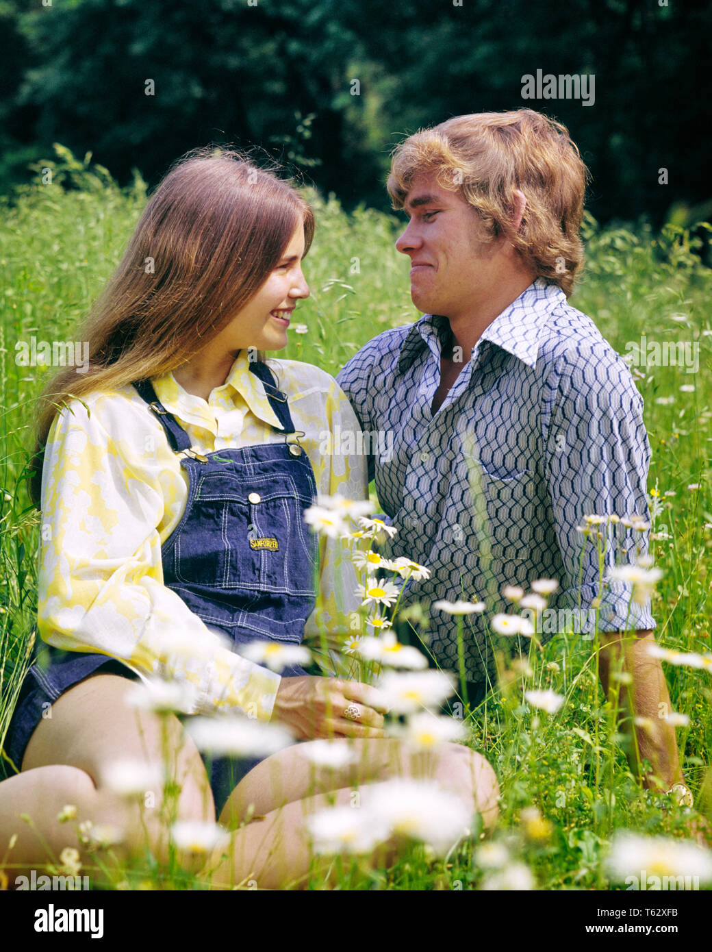 1970s SMILING ROMANTIC TEEN COUPLE SITTING TOGETHER IN FIELD OF DAISIES AND WILD FLOWERS - kj6263 HAR001 HARS NOSTALGIA OLD FASHION 1 JUVENILE FACIAL COMMUNICATION STRONG WILD PLEASED JOY LIFESTYLE FEMALES RURAL HALF-LENGTH PERSONS CARING MALES TEENAGE GIRL TEENAGE BOY EXPRESSIONS DATING DAISIES TEMPTATION DREAMS HAPPINESS CHEERFUL DISCOVERY AND CHOICE EXCITEMENT IN OF ATTRACTION SMILES CONNECTION COURTSHIP CONCEPTUAL JOYFUL STYLISH TEENAGED PERSONAL ATTACHMENT POSSIBILITY QUEEN ANNE'S LACE AFFECTION EMOTION GROWTH JUVENILES SMIRKING SOCIAL ACTIVITY CAUCASIAN ETHNICITY COURTING HAR001 Stock Photo