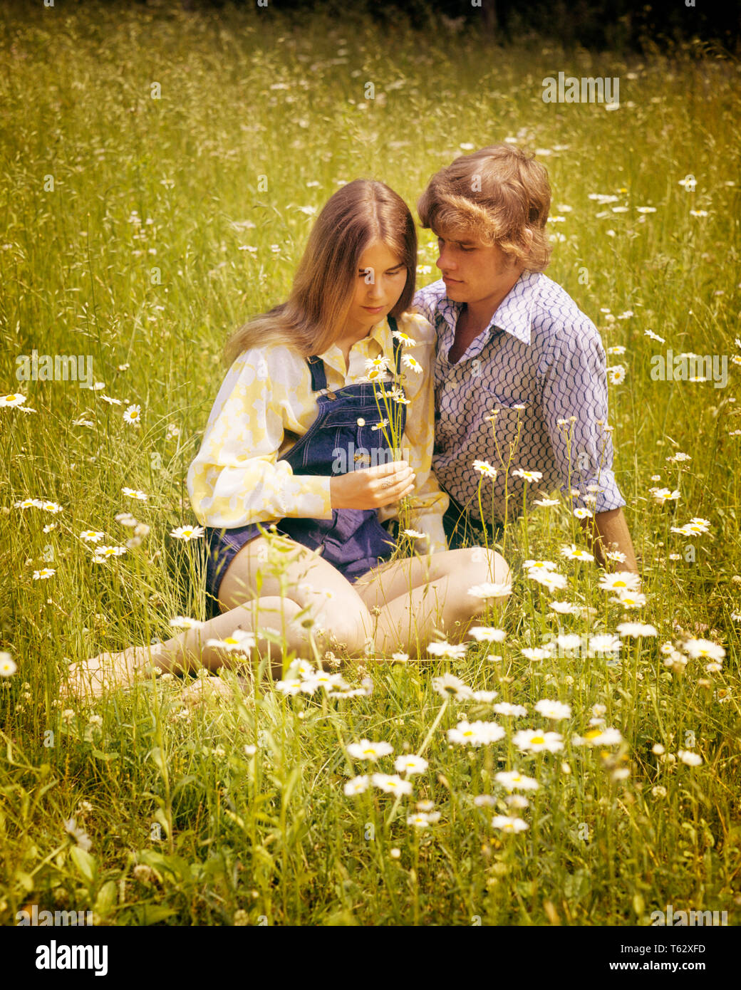 1970s ROMANTIC TEEN COUPLE IN FIELD OF DAISIES - kj6266 HAR001 HARS COPY SPACE FRIENDSHIP HALF-LENGTH PERSONS CARING MALES TEENAGE GIRL TEENAGE BOY DENIM SUMMERTIME DATING DAISIES HAPPINESS HIGH ANGLE HAIRSTYLE ATTRACTION RELATIONSHIPS CONNECTION COURTSHIP HAIRSTYLES STYLISH TEENAGED POSSIBILITY JUVENILES SOCIAL ACTIVITY TOGETHERNESS CAUCASIAN ETHNICITY COURTING HAR001 OLD FASHIONED Stock Photo
