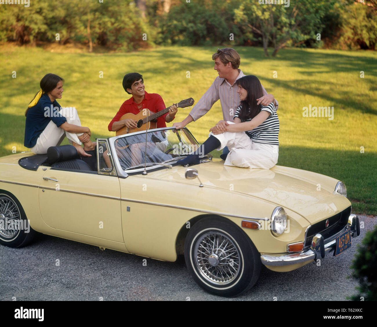 1970s TWO TEENAGE COUPLES SITTING ON CREAM COLOR MG CONVERTIBLE SPORTS CAR SUMMERTIME FUN DATING MUSIC BOY PLAYING GUITAR - km2869 PHT001 HARS VEHICLE TEAMWORK STRONG JOY LIFESTYLE SOUND GROWNUP HOME LIFE COMMUNICATING TRANSPORT COPY SPACE FRIENDSHIP FULL-LENGTH HALF-LENGTH GROWN-UP AUTOMOBILE CARING TEENAGE GIRL TEENAGE BOY CONFIDENCE TRANSPORTATION SUMMERTIME HAPPINESS HIGH ANGLE SUMMER SEASON MOTOR VEHICLE RECREATION MG MOTORING CONNECTION CONCEPTUAL MOBILITY STYLISH TEENAGED PERSONAL ATTACHMENT AFFECTION COMMUNICATE EMOTION RELAXATION SEASON TOGETHERNESS CAUCASIAN ETHNICITY OLD FASHIONED Stock Photo
