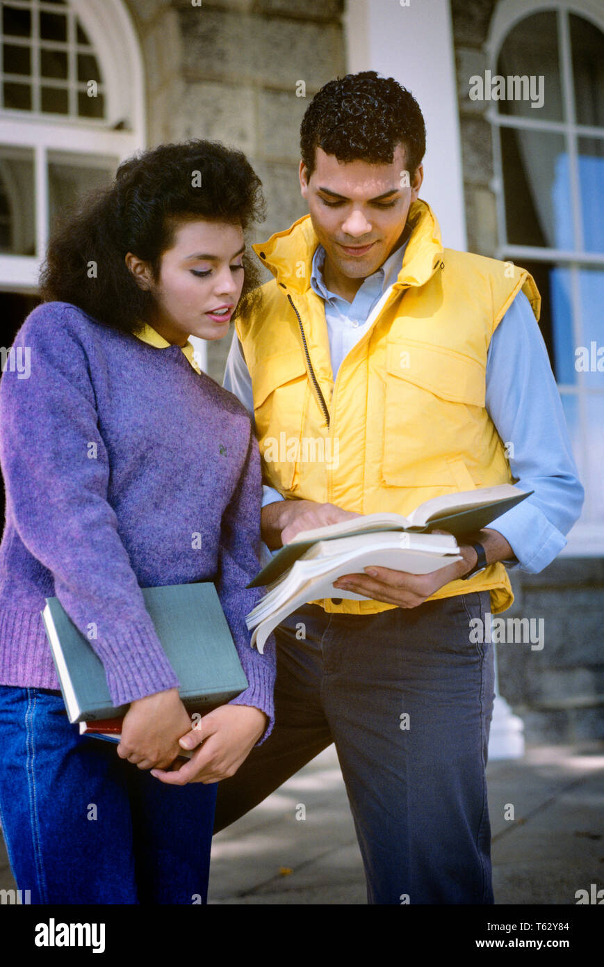 1980s AFRICAN AMERICAN COLLEGE COUPLE LOOKING AT TEXTBOOK - ks24461 DEG002 HARS ETHNIC SWEATER NOSTALGIC PAIR YELLOW DIVERSITY COLOR SHARING JEANS OLD TIME NOSTALGIA OLD FASHION JUVENILE STYLE COMMUNICATION YOUNG ADULT INFORMATION SONS LIFESTYLE CAMPUS FEMALES COPY SPACE FRIENDSHIP HALF-LENGTH PERSONS RACIAL MALES AMERICANS DENIM SHARE PURPLE STYLES UNIVERSITIES AFRICAN-AMERICANS AFRICAN-AMERICAN KNOWLEDGE LOW ANGLE ETHNIC DIVERSITY AFRO-AMERICAN AFRO-AMERICANS HIGHER EDUCATION CONNECTION BLACKS STYLISH TEENAGED COLLEGES COOPERATION FASHIONS HIGHER JUVENILES YOUNG ADULT MAN YOUNG ADULT WOMAN Stock Photo