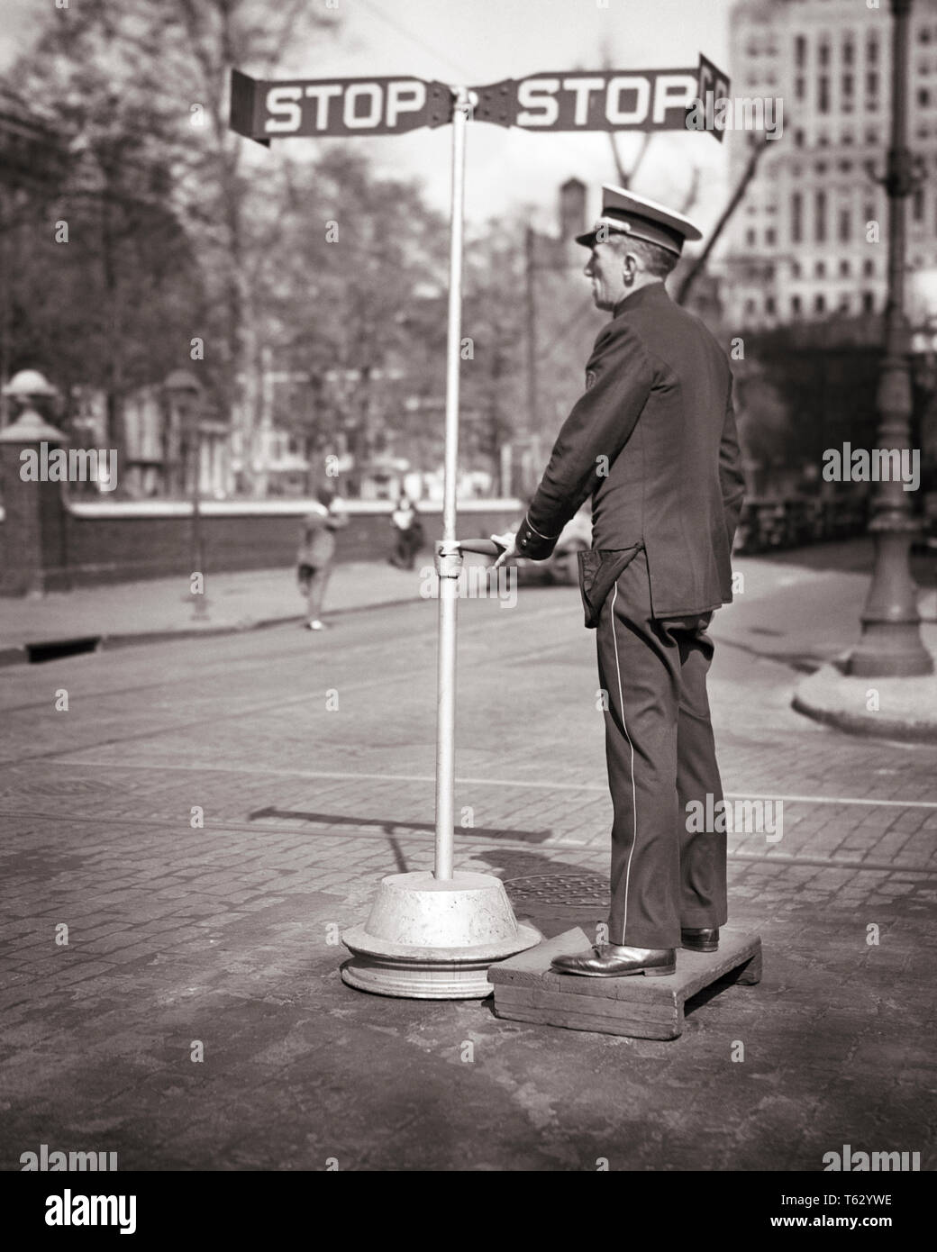 1940s TRAFFIC POLICEMAN STANDING WOODEN BOX WITH HAND-OPERATED SEMAPHORE SET AT STOP AT INDEPENDENCE SQUARE PHILADELPHIA PA USA - q41871 CPC001 HARS TRANSPORTATION B&W COP PROTECT AND SERVE PA DIRECTION OCCUPATIONS UNIFORMS OFFICERS POLICEMEN SEMAPHORE COOPERATION COPS HAND-OPERATED MID-ADULT MID-ADULT MAN SOLUTIONS BADGE BADGES BLACK AND WHITE CAUCASIAN ETHNICITY CITY OF BROTHERLY LOVE OLD FASHIONED Stock Photo