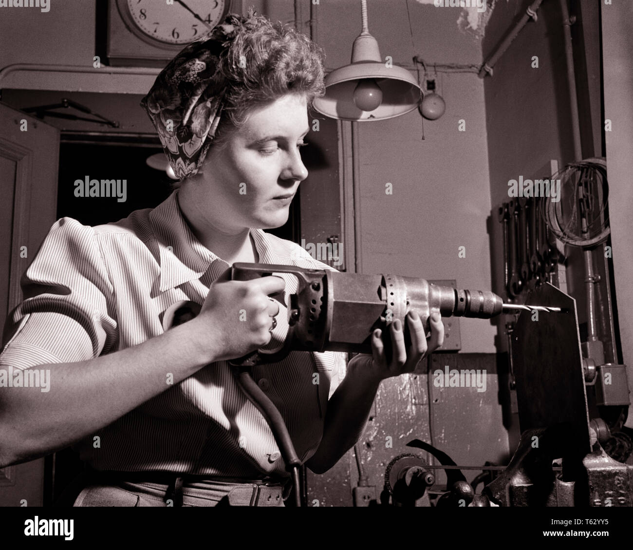 1940s PATRIOTIC ANONYMOUS UNIDENTIFIED WOMAN HOME FRONT INDUSTRIAL WORKER USING ELECTRICAL HAND DRILL DURING WORLD WAR II - q43367 CPC001 HARS FEMALES WW2 JOBS HALF-LENGTH LADIES PERSONS INSPIRATION CONFIDENCE B&W GOALS SUCCESS SKILL OCCUPATION SKILLS HOME FRONT STRENGTH VICTORY COURAGE CHOICE KNOWLEDGE LOW ANGLE POWERFUL WORLD WARS LABOR PRIDE WORLD WAR WORLD WAR TWO WORLD WAR II AUTHORITY EMPLOYMENT OCCUPATIONS UNIDENTIFIED USING CONCEPTUAL PATRIOTIC ROSIE THE RIVETER STYLISH WORLD WAR 2 ANONYMOUS EMPLOYEE PRECISION YOUNG ADULT WOMAN BLACK AND WHITE CAUCASIAN ETHNICITY DURING LABORING Stock Photo