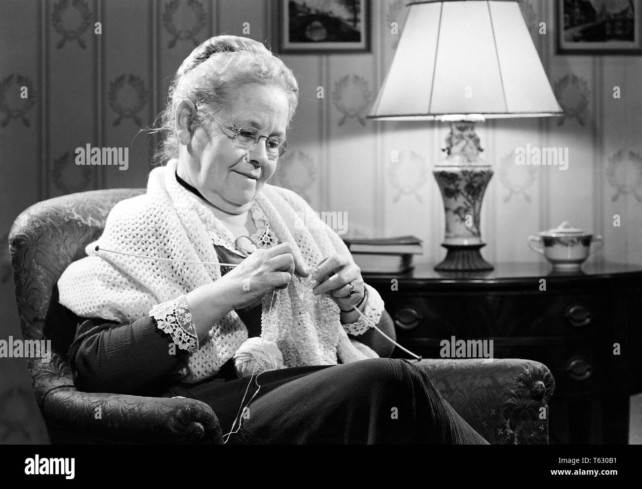 1950s WOMAN SMILING GRANDMOTHER WEARING GRANNY GLASSES SHAWL SITTING KNITTING - s10005 RCH001 HARS JOY LIFESTYLE SATISFACTION PARENTING ELDER FEMALES GRANDPARENT RELATION GROWNUP HOME LIFE HALF-LENGTH LADIES PERSONS GROWN-UP GRANNY SERENITY CONFIDENCE EYEGLASSES SENIOR ADULT B&W SENIOR WOMAN HAPPINESS OLD AGE OLDSTERS CHEERFUL OLDSTER LEISURE EYE WEAR KNOWLEDGE RECREATION PRIDE RELATIONSHIPS SHAWL SMILES ELDERS JOYFUL STYLISH GRANNY GLASSES ELDERLY WOMAN PARENTAL PARENTHOOD PEOPLE ADULTS RELAXATION TOGETHERNESS BLACK AND WHITE CAUCASIAN ETHNICITY OLD FASHIONED Stock Photo