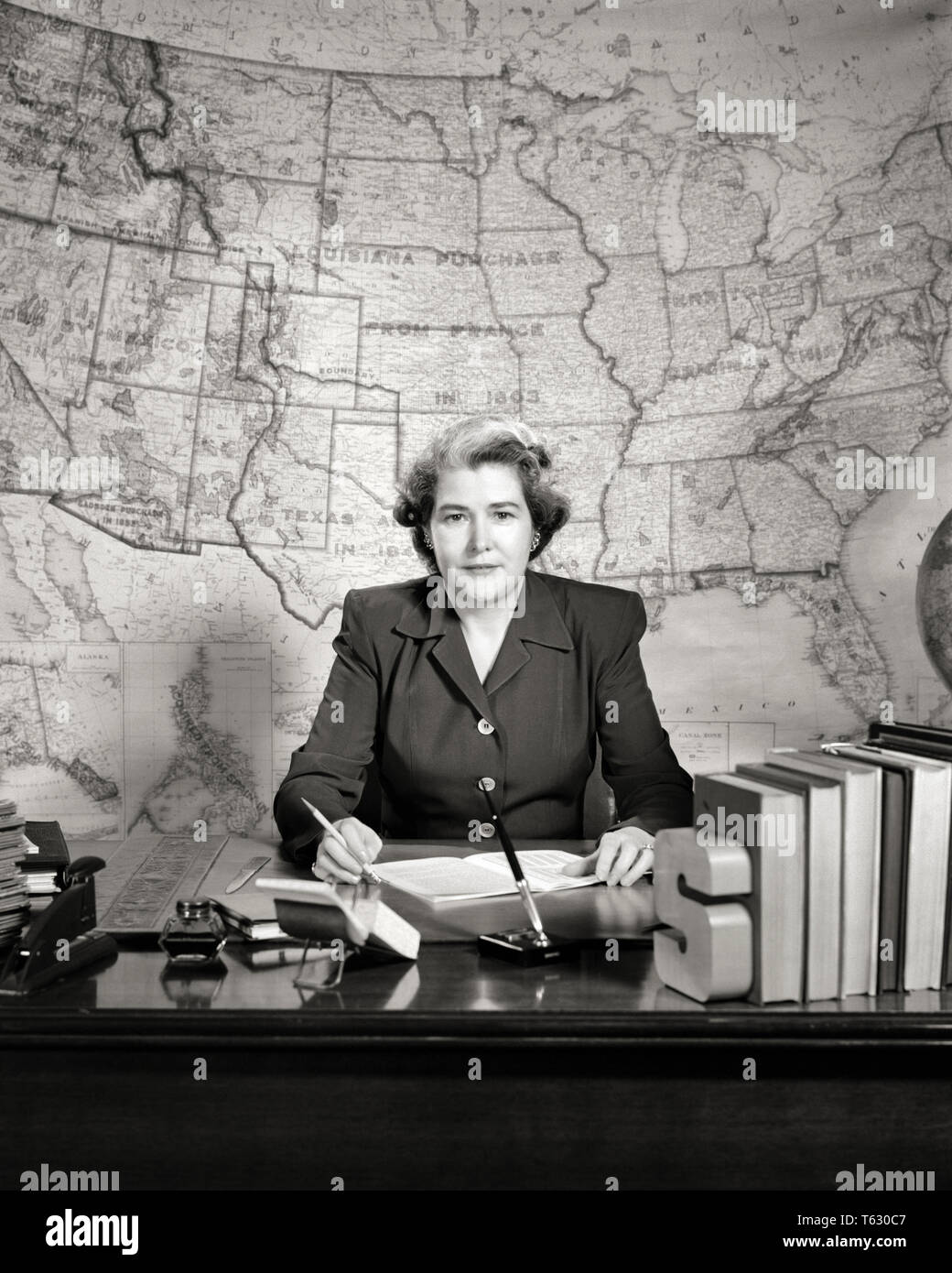 1950s-school-geography-teacher-sitting-at-desk-looking-at-camera-serious-facial-expression-map-of-the-usa-on-wall-behind-s1111-har001-hars-copy-space-half-length-ladies-persons-inspiration-united-states-of-america-confidence-expressions-bw-geography-eye-contact-goals-schools-grade-hairstyle-instructor-leadership-stern-at-of-on-the-authority-high-school-occupations-primary-high-schools-educator-stylish-k-12-educating-educators-facial-expression-grade-school-gray-streak-instructors-mid-adult-mid-adult-woman-school-teaches-black-and-white-caucasian-ethnicity-har001-old-fashioned-T630C7.jpg