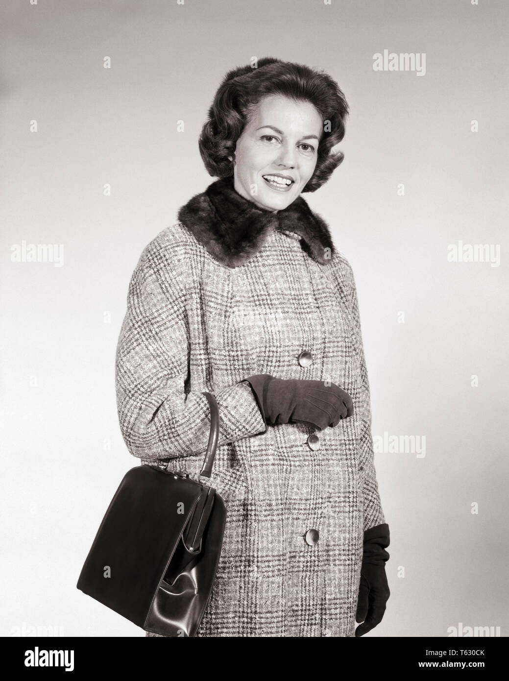 1960s BRUNETTE WOMAN WEARING GLEN PLAID WOOL COAT WITH FUR COLLAR CARRYING POCKETBOOK STANDING OUTDOOR TALKING LOOKING AT CAMERA - s11593 HAR001 HARS COMMUNICATION PLEASED JOY LIFESTYLE SATISFACTION FEMALES WOOL COPY SPACE HALF-LENGTH LADIES PERSONS PLAID CONFIDENCE EXPRESSIONS B&W EYE CONTACT BRUNETTE SUCCESS HOMEMAKER HOMEMAKERS CHEERFUL LEISURE STRENGTH STYLES CHOICE LEADERSHIP PRIDE HOUSEWIVES SMILES FUR COLLAR CONCEPTUAL JOYFUL STYLISH POCKETBOOK FASHIONS MID-ADULT MID-ADULT WOMAN BLACK AND WHITE CAUCASIAN ETHNICITY HAR001 OLD FASHIONED Stock Photo