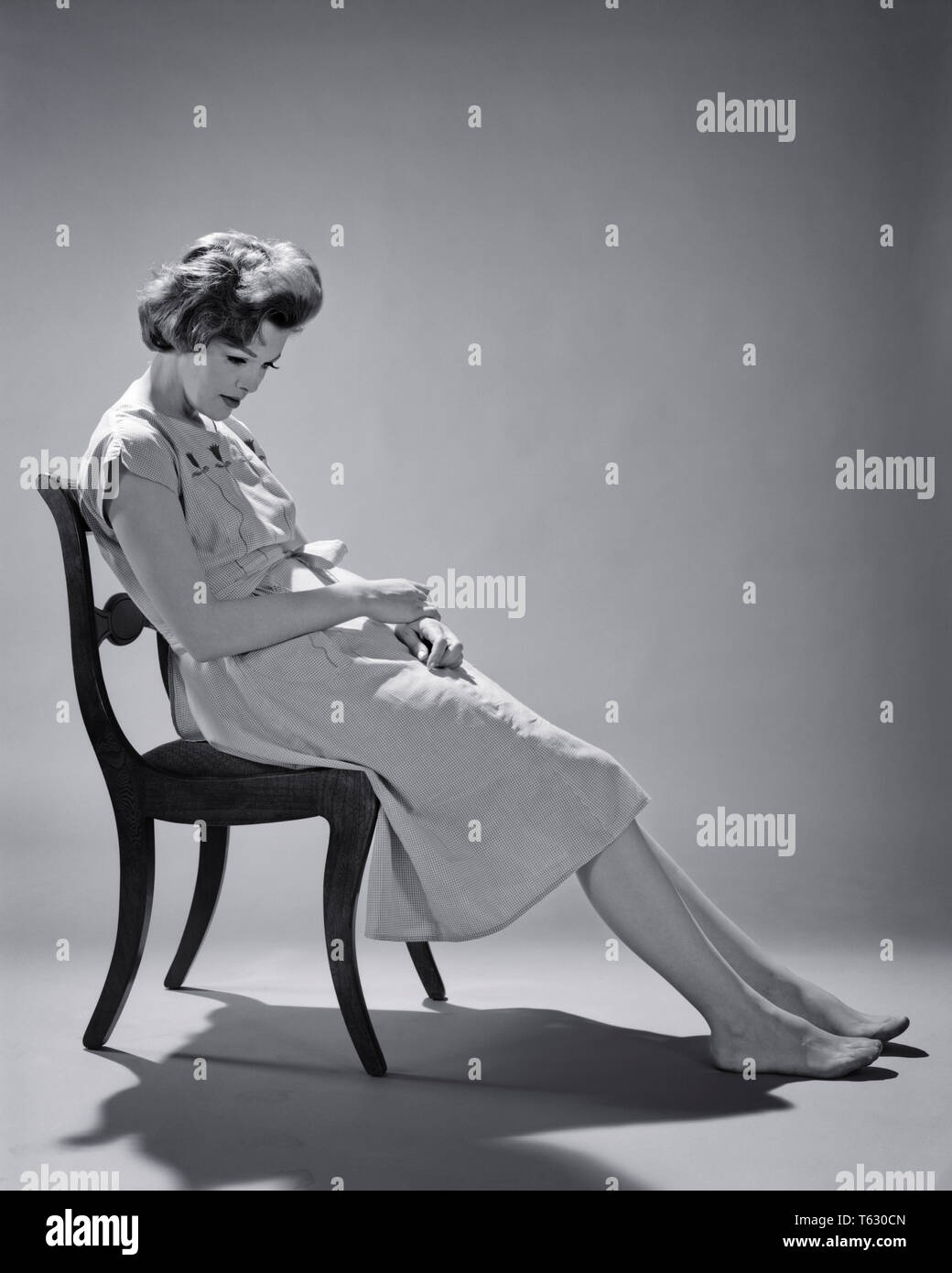 1960s EXHAUSTED DEPRESSED WOMAN SLUMPED SITTING ON CHAIR NOT WEARING SHOES - s11680 HAR001 HARS NERVOUS EXPRESSIONS TROUBLED B&W SADNESS HEALTHCARE HOMEMAKER ANXIETY HOMEMAKERS PREVENTION HEALING DIAGNOSIS DESPAIR NOT HEALTH CARE HOUSEWIVES IMPAIRMENT MOOD SLUMPED TREATMENT MENTAL HEALTH CONCEPTUAL GLUM TENSION MID-ADULT MID-ADULT WOMAN MISERABLE YOUNG ADULT WOMAN BLACK AND WHITE CAUCASIAN ETHNICITY DISEASE HAR001 MENTAL ILLNESS OLD FASHIONED Stock Photo